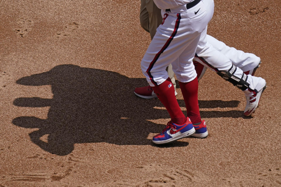 Chicago White Sox's Luis Robert, center, leaves with a team trainer and first base coach Daryl Boston during the first inning of a baseball game against the Cleveland Indians in Chicago, Sunday, May 2, 2021. (AP Photo/Nam Y. Huh)