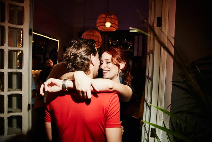 Two people embracing and smiling in a warmly lit indoor setting