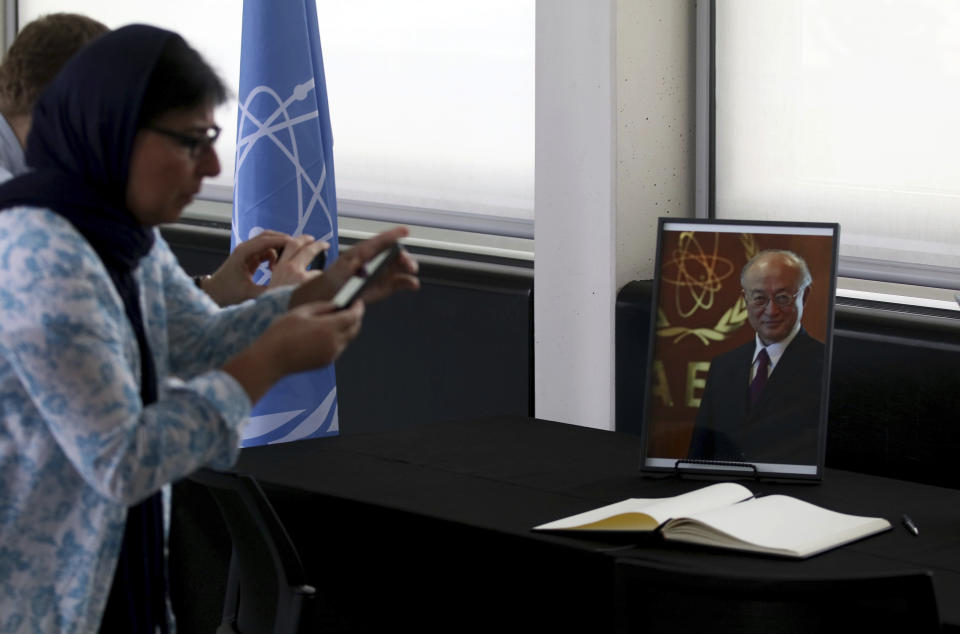 People take a pictures of the condolence book and a portrait photo of Director General of the International Atomic Energy Agency, IAEA, Yukiya Amano from Japan in Vienna, Austria, Monday, July 22, 2019. The IAEA announced the death of the agency's Director General Yukiya Amano at the age of 72 years. (AP Photo/Ronald Zak)