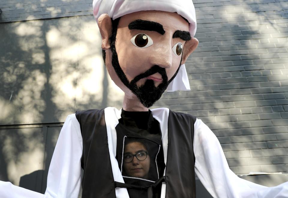 In this Saturday, July 27, 2019 photo, a woman looks from inside a puppet presents the outfit of Iran's Khorasan region, before starting the performance to showcase the theme of this year's festival "UNITY" during the Tirgan summer festival at the Harbourfront Centre in Toronto, Canada. The event aims to preserve and celebrate Iranian and Persian culture, said festival CEO Mehrdad Ariannejad. Among those who attended were second-and third-generation immigrants, many of whom have never been to Iran or have not been there since leaving the country following the 1979 Islamic Revolution. (AP Photo/Kamran Jebreili)