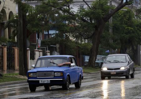 A man tries to adjust the windshield wiper of his Lada while driving in the rain in Havana February 8, 2015. REUTERS/Enrique De La Osa