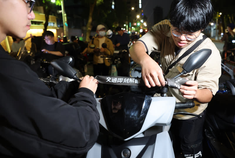 機車路權團體立院前集結遊行（1） 台灣機車路權促進會30日晚間在立法院前發起「路邊 臨停不放任，禁行惡法應廢除」機車遊行，並製作 「交通即刻解嚴」等標語布條發送給與會騎士。 中央社記者趙世勳攝　113年3月30日 