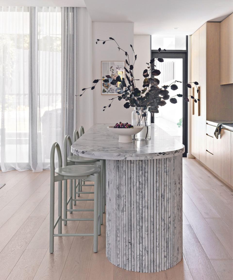 Kitchen with marble kitchen island in the center and wood cabinetry to the right