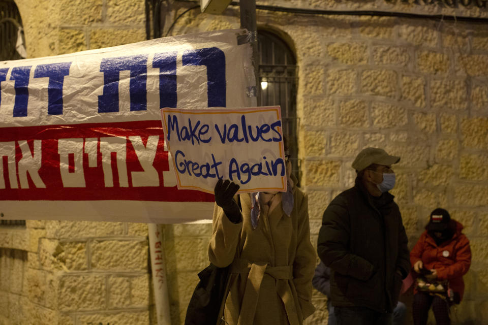 A protester holds a placard outside of Israeli Prime Minister Benjamin Netanyahu's official residence in Jerusalem, Saturday, Jan. 16, 2021. (AP Photo/Maya Alleruzzo)