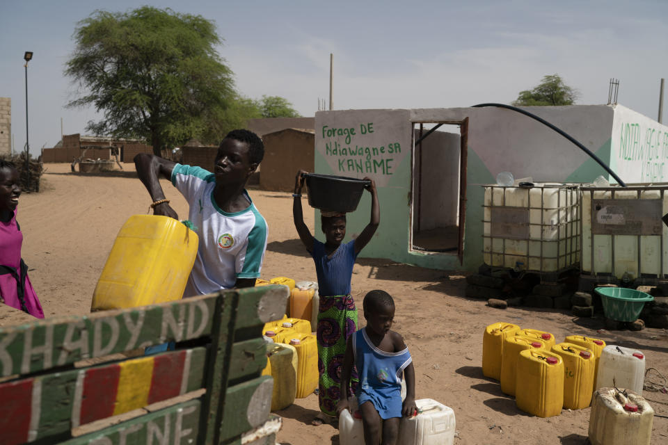 A girl carries a bucket of water from a community well in the village of Ndiawagne Fall in Kebemer, Senegal, on Friday, Nov. 5, 2021. The region is on one end of a project called the Great Green Wall that was once envisioned as a way for Africa to fight climate change. The idea behind the stalled project was to plant a 5,000-mile line of trees that would span the entire continent and hold back the Sahara Desert. (AP Photo/Leo Correa)