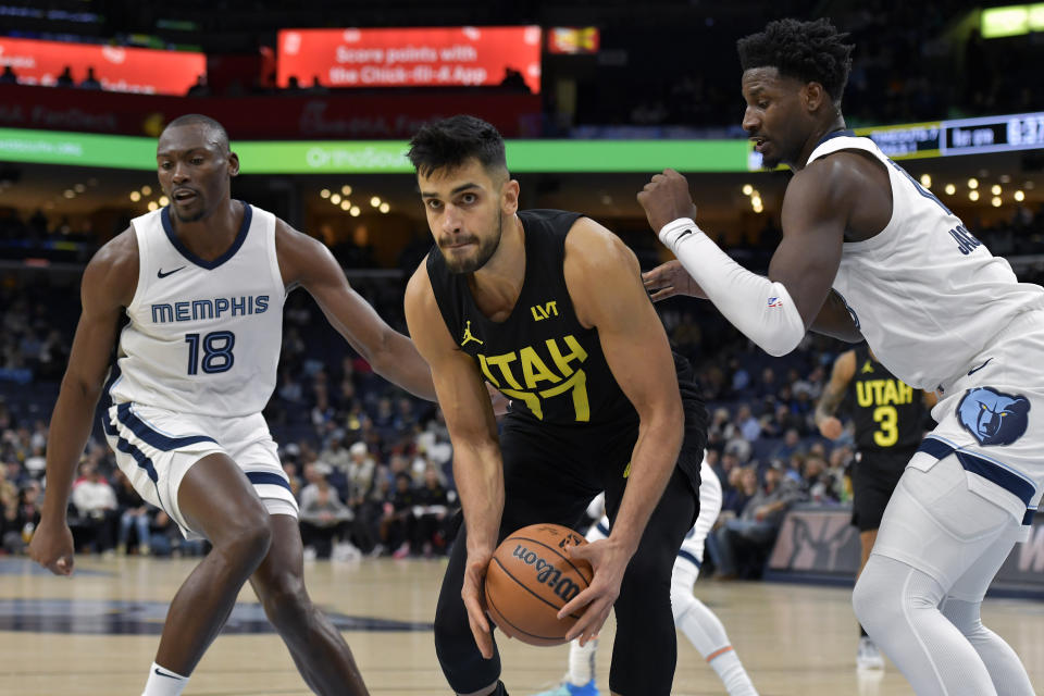 Utah Jazz center Omer Yurtseven (77) handles the ball between Memphis Grizzlies center Bismack Biyombo (18) and forward Jaren Jackson Jr. in the first half of an NBA basketball game Wednesday, Nov. 29, 2023, in Memphis, Tenn. (AP Photo/Brandon Dill)