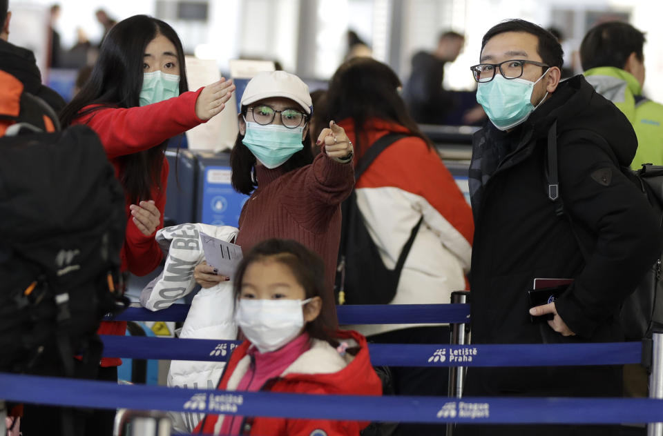 Passengers wearing masks wait in a line to check-in to a flight to Shanghai at the Vaclav Havel International Airport in Prague, Czech Republic, Monday, Jan. 27, 2020. Prague's international airport is launching an information campaign for travellers who develop symptoms possibly linked to a new coronavirus illness. (AP Photo/Petr David Josek)