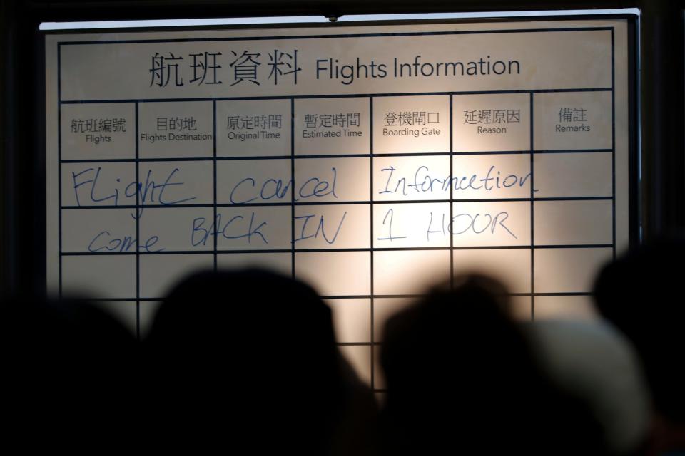 Travelers gather near a flights information board at the Hong Kong International airport.