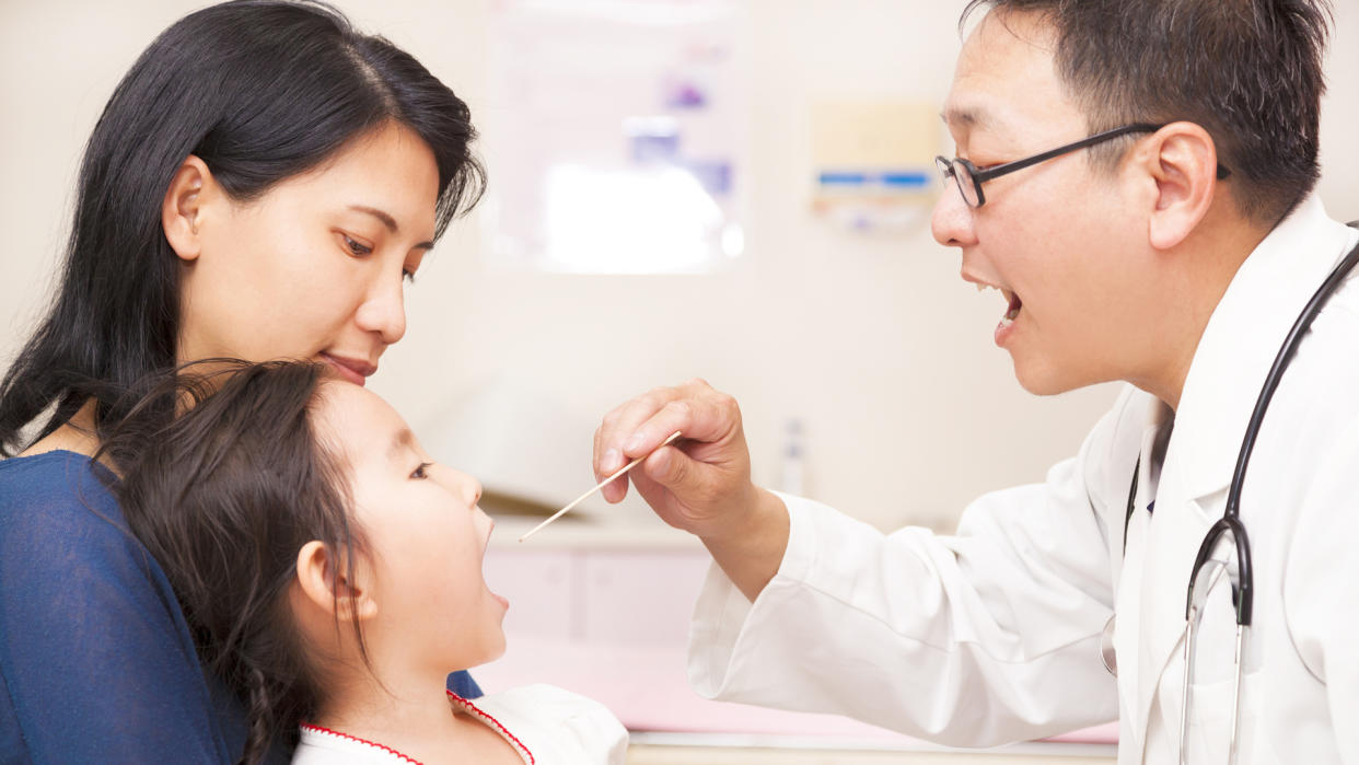 Pediatrician checking little girl throat.