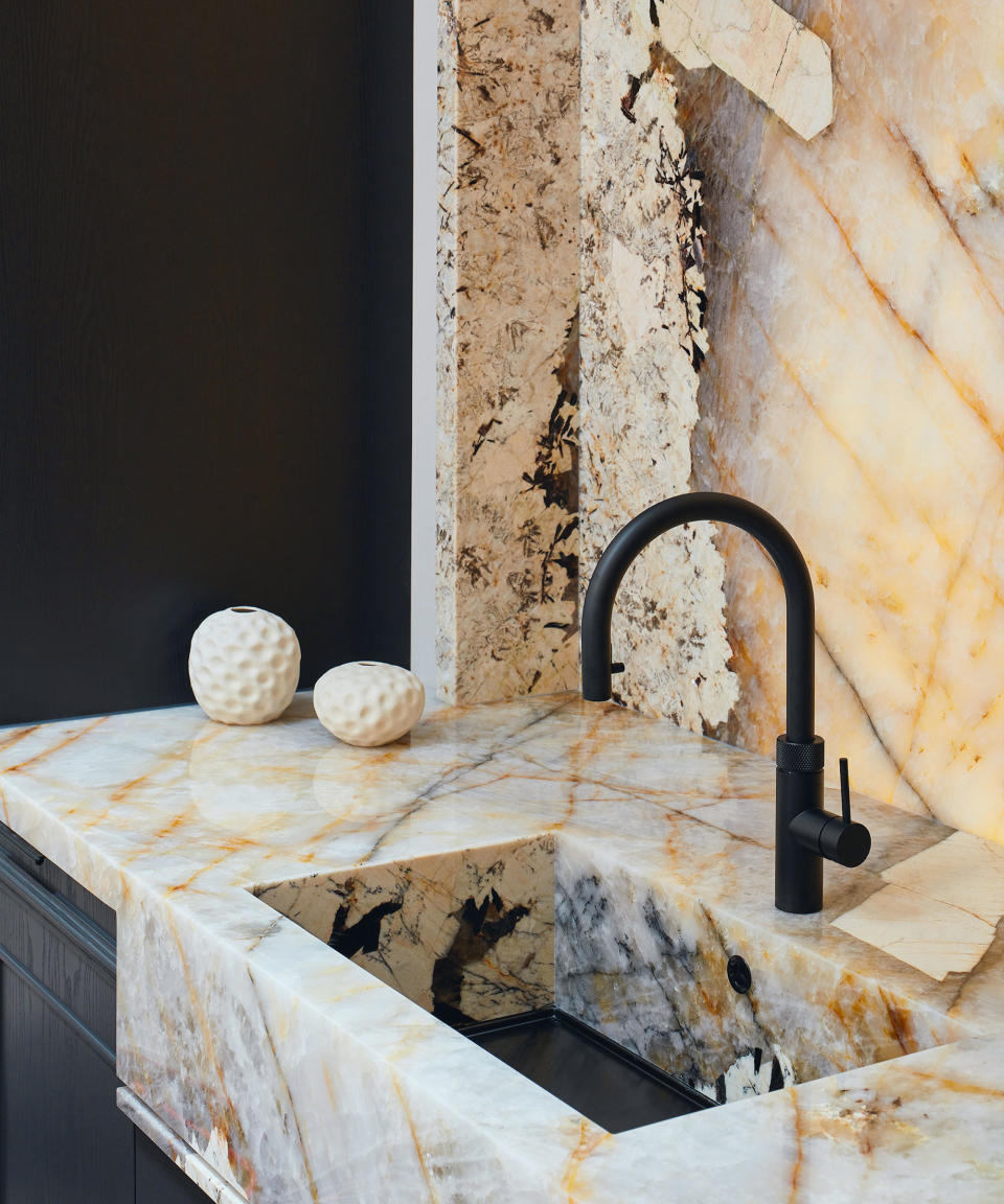 Close up of marble splashback and countertop, black tap