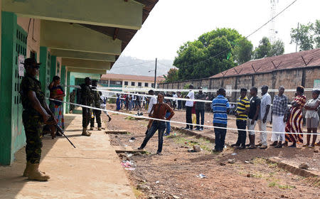 Military members stand guard as people queue to cast their vote during a presidential run-off in Freetown, Sierra Leone March 31, 2018. REUTERS/Olivia Acland