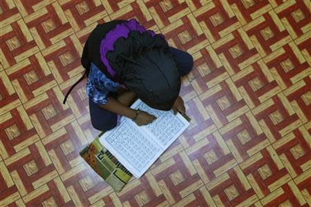 A Rohingya girl reads the Koran on the floor of the family's rented house in Cheras Baru, Kuala Lumpur March 2, 2014. REUTERS/Samsul Said