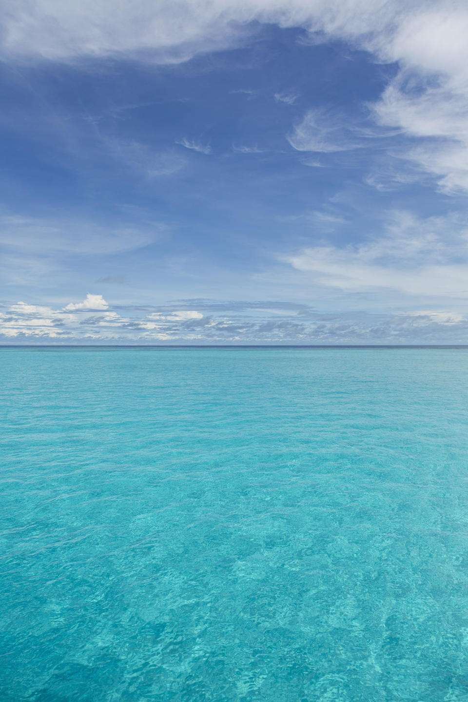 View of clear tropical water of Indian ocean with blue sky and clouds off coast of Baa Atoll, Maldives