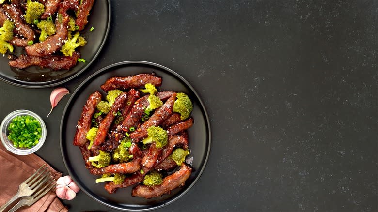 Beef and broccoli on black plates 