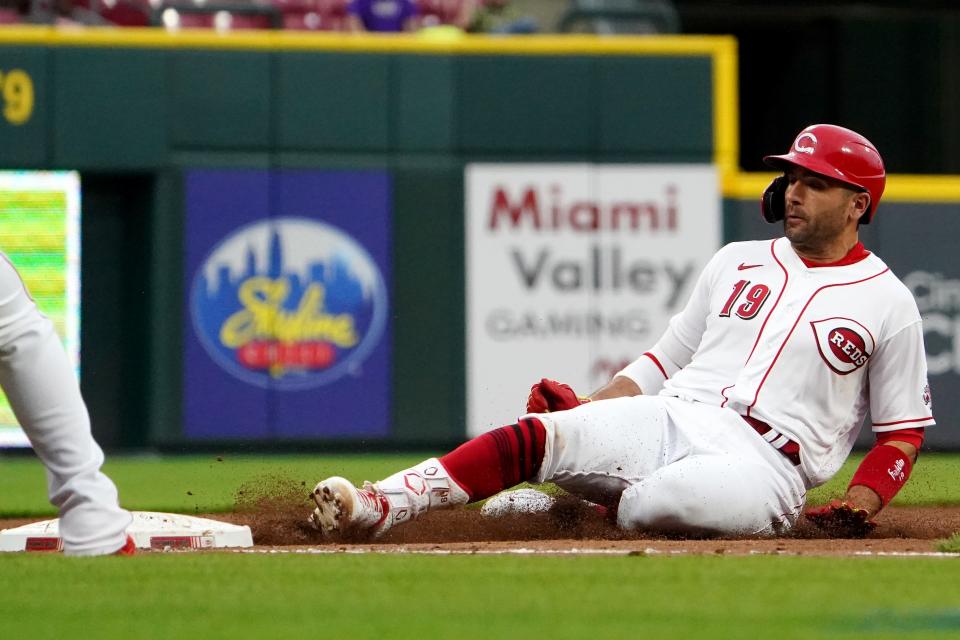 Cincinnati Reds first baseman Joey Votto (19) slides in safely at third base for a triple in the third inning during a baseball game against the Chicago Cubs, Wednesday, May 25, 2022, at Great American Ball Park in Cincinnati. 
