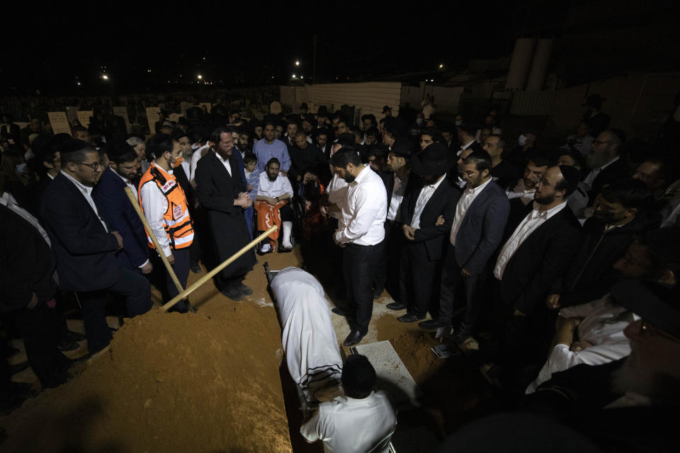 Mourners gather around the grave during the funeral of Yedidyia Chiyuis at a cemetery in Petah Tikva, Sunday, May 2, 2021. A stampede at a religious festival attended by tens of thousands of ultra-Orthodox Jews in northern Israel killed dozens of people and injured about 150 early Friday, medical officials said. It was one of the country's deadliest civilian disasters. (AP Photo/Sebastian Scheiner)