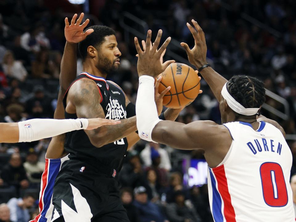 Los Angeles Clippers guard Paul George passes the ball against Detroit Pistons center Jalen Duren (0) during the first half of an NBA basketball game, Monday, Dec. 26, 2022, in Detroit. (AP Photo/Duane Burleson)