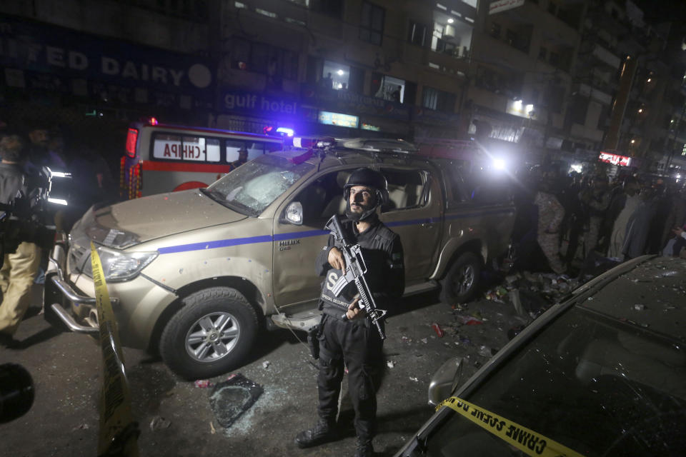 A Pakistani police officer stands next to a damaged vehicle at the site of bomb explosion, in Karachi, Pakistan, Thursday, May 12, 2022. A roadside bombing targeted a van carrying Pakistani security forces in the southern port city of Karachi on Thursday, killing and wounding few people, police said. (AP Photo/Fareed Khan)
