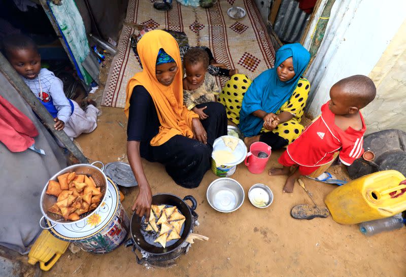 An internally displaced Somali woman and her children prepare their Iftar meal during the month of Ramadan at the Shabelle makeshift camp in Hodan district of Mogadishu