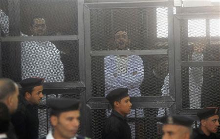 Political activists Ahmed Maher (R), Ahmed Douma (C) and Mohamed Adel, founder of 6 April movement, look on from behind bars in Abdeen court in Cairo, December 22, 2013. REUTERS/Stringer