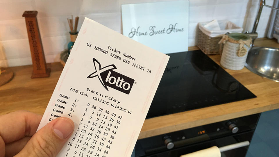 A Saturday X Lotto player holds a quickpick ticket in the kitchen of their new home.