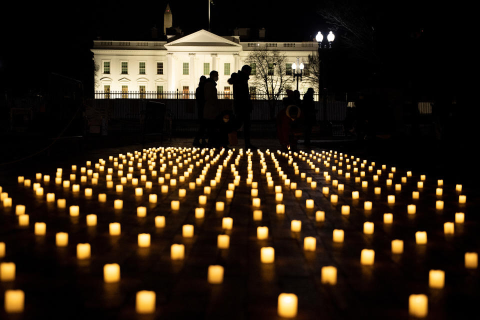 People walk past electric candles from a vigil in Lafayette Park oin Washington, D.C., for nurses who died during the COVID-19 pandemic.