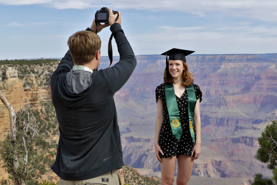 Andrew Fink takes a photo of recent Baylor University graduate Cady Malachowski at the Grand Canyon Friday, May 15, 2020, in Grand Canyon, Ariz. Tourists are once again roaming portions of Grand Canyon National Park when it partially reopened Friday morning, despite objections that the action could exacerbate the coronavirus pandemic. (AP Photo/Matt York)