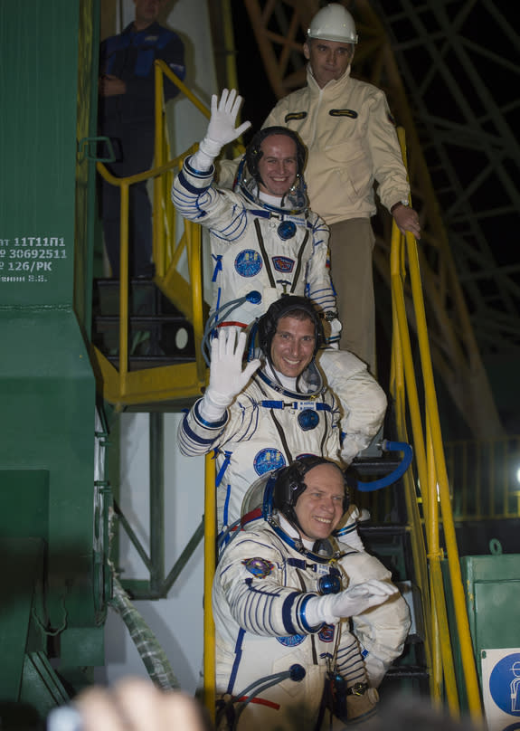 American astronaut Mike Hopkins (center) and Russian cosmonauts Oleg Kotov (bottom) and Sergey Ryazanskiy wave just before boarding their Soyuz TMA-10M spacecraft during a launch to the International Space Station on Thursday, Sept. 26 from Ba