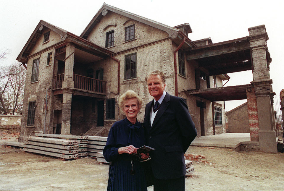 HUAIYIN, CHINA:  Billy Graham, the American evangelist and his wife Ruth smile, 19 April 1988 as they pose in front Ruth birthplace in Huaiyin, Jiangsu province, China. Graham, (son of a dairy farmer, born in 1918 in Charlotte, NC), attended Florida Bible Institute and was ordained a Southern Baptist minister in 1939 and quickly gained a reputation as a preacher. During the 1950s he conducted a series of highly organized revivalist campaigns in the USA and UK, and later in South America, the USSR and Western Europe. (Photo credit should read JOHN GIANNINI/AFP/Getty Images)