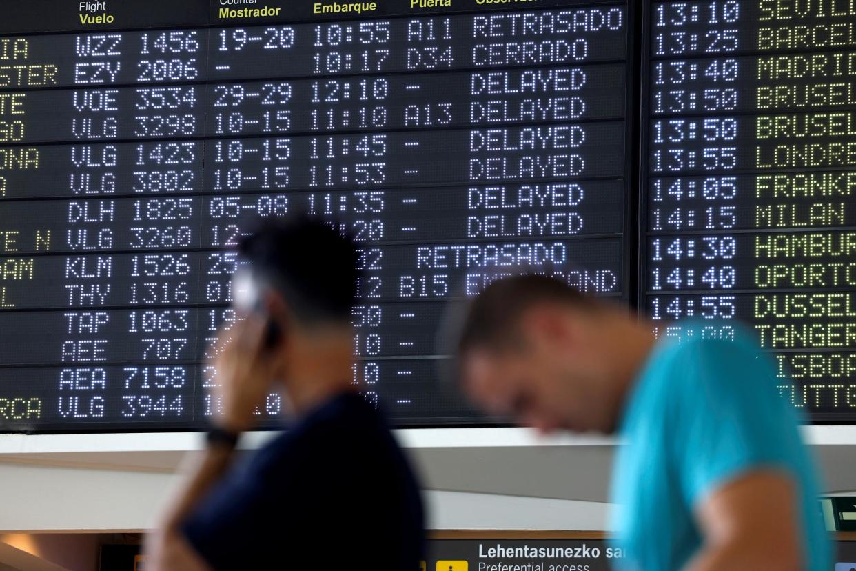 <span>Passengers wait in front of a board displaying delayed flight information at Bilbao Airport in Bilbao, Spain, on 19 July 2024.</span><span>Photograph: Vincent West/Reuters</span>