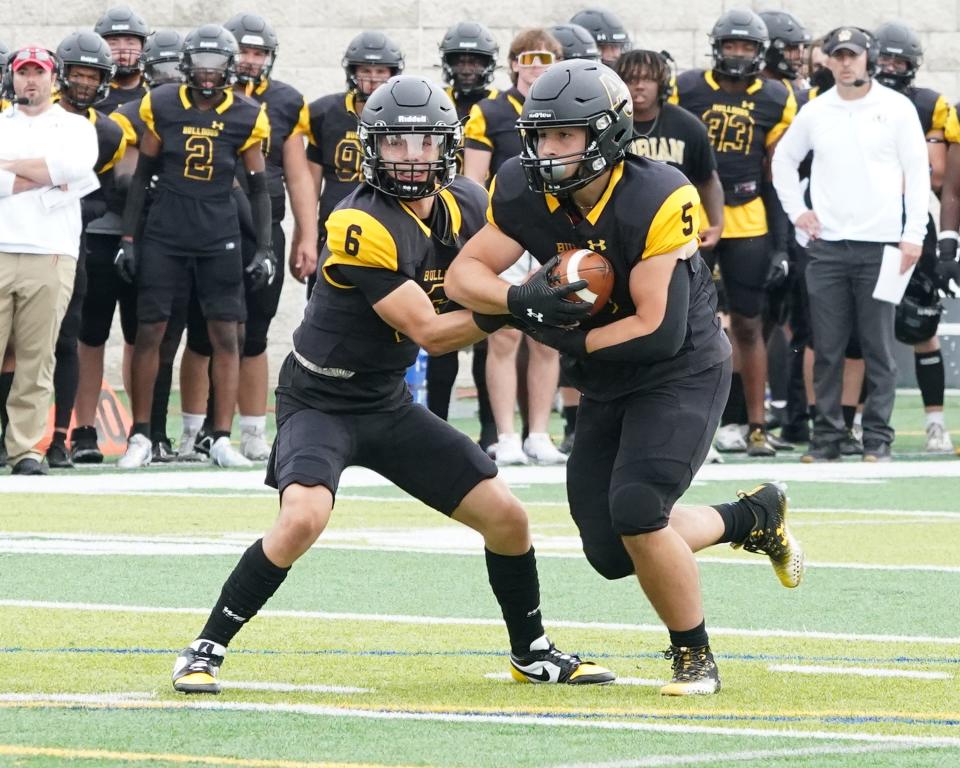 Adrian College's Mark Lopez hands the ball off to Salvatore Patierno during Saturday's game against Bluffton.