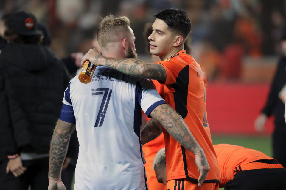 Sporting Kansas City forward Johnny Russell (7) and Houston Dynamo defender Franco Escobar, right, hug after the Dynamo's win in extra minutes after the second half of an MLS playoff soccer match Sunday, Nov. 26, 2023, in Houston. (AP Photo/Michael Wyke)