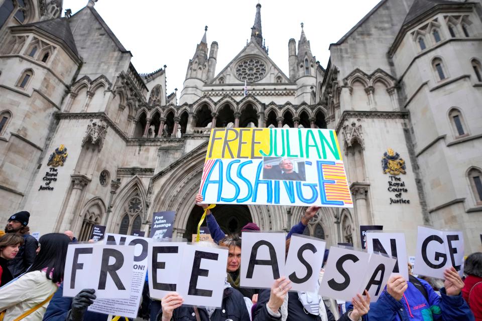 Demonstrators hold banners outside the Royal Courts of Justice in London, Tuesday, Feb. 20, 2024.