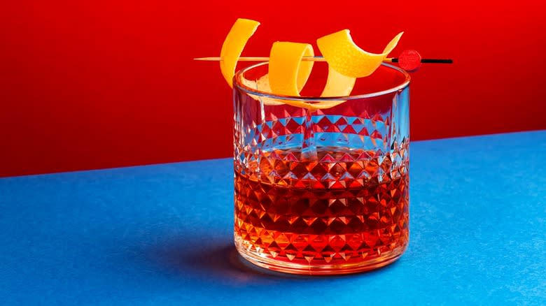 A Sazerac cocktail with a blue and red background