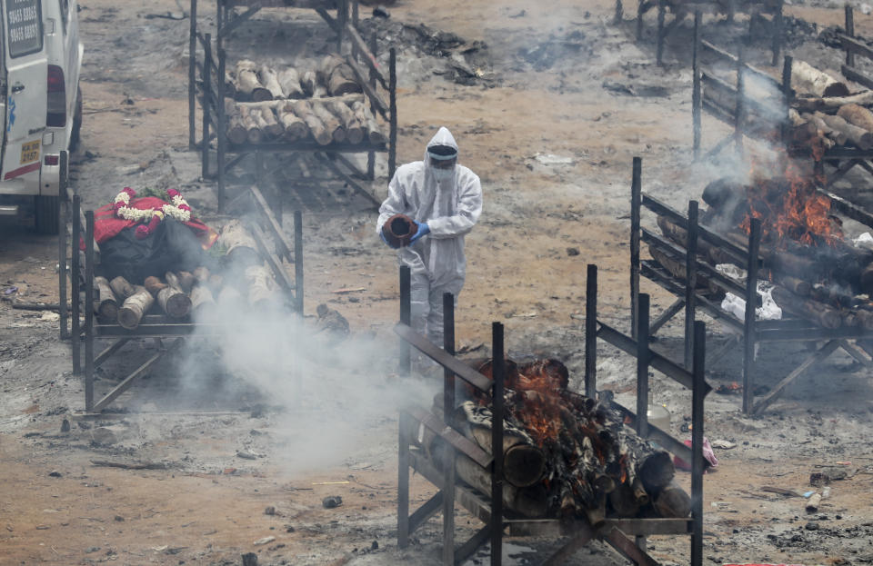 A man performs rituals as bodies of people who died of COVID-19 are cremated at an open crematorium on the outskirts of Bengaluru, Karnataka state, India, Wednesday, May 12, 2021. (AP Photo/Aijaz Rahi)