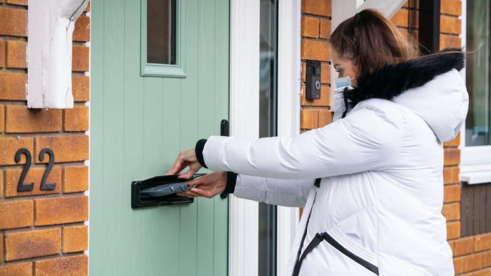 A volunt&#xe1;ria Hanna Taylor entrega kits de teste de coronav&#xed;rus de porta em porta em Woking, Surrey