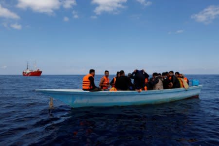 Libyan migrants on a wooden boat await rescue by the migrant search and rescue vessel MV Seefuchs (rear) of the German NGO Sea-Eye south of the Al Jurf Oilfield some 45 nautical miles off the coast of Libya, October 1, 2017. REUTERS/Darrin Zammit Lupi