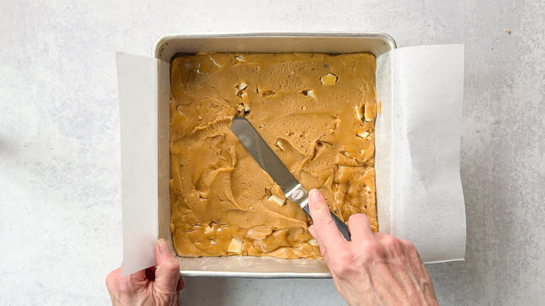 Spreading white chocolate blondie batter into baking pan with spatula