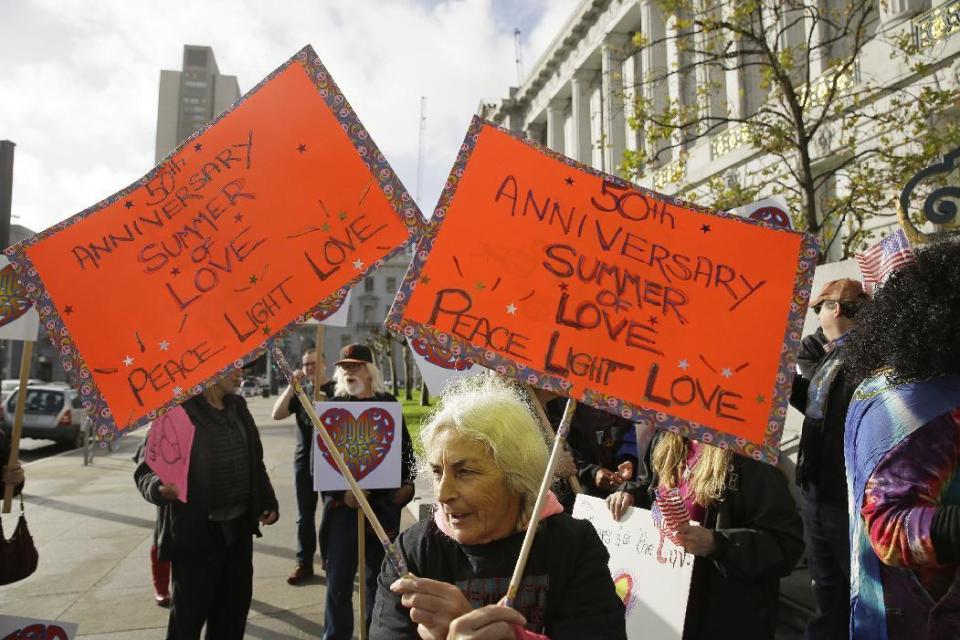Ruth Wechsler waves a pair of signs in support of a Summer of Love anniversary concert during a protest outside City Hall Thursday, Feb. 16, 2017, in San Francisco. The show might still go on but a concert planned to mark the 50th anniversary of the Summer of Love has hit another major bureaucratic hurdle. San Francisco's Recreation and Park Commission on Thursday upheld its decision earlier this month to deny a permit for the concert. (AP Photo/Eric Risberg)