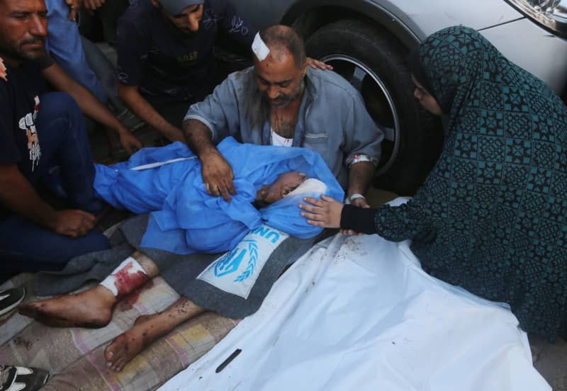 Relatives of Palestinians killed in Israeli attacks mourn as they receive the dead bodies from the morgue of Al-Aqsa Hospital for burial in Deir El-Balah. Omar Ashtawy/APA Images via ZUMA Press Wire/dpa