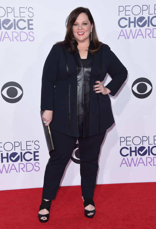 Melissa McCarthy in a black suit with leather detailing.