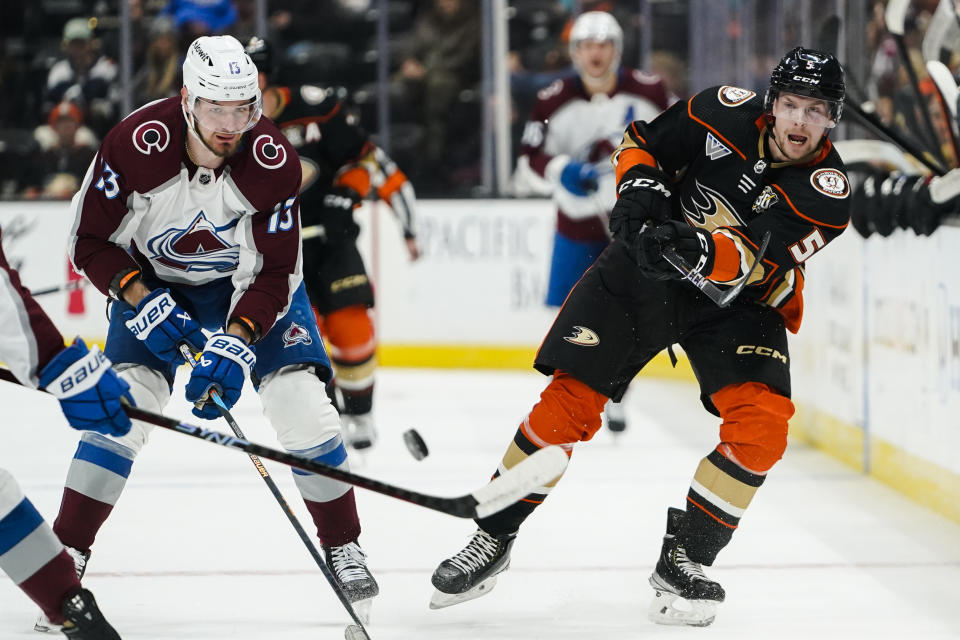 Anaheim Ducks defenseman Urho Vaakanainen (5) sends the puck ahead as Colorado Avalanche right wing Valeri Nichushkin (13) defends during the first period of an NHL hockey game Saturday, Dec. 2, 2023, in Anaheim, Calif. (AP Photo/Ryan Sun)