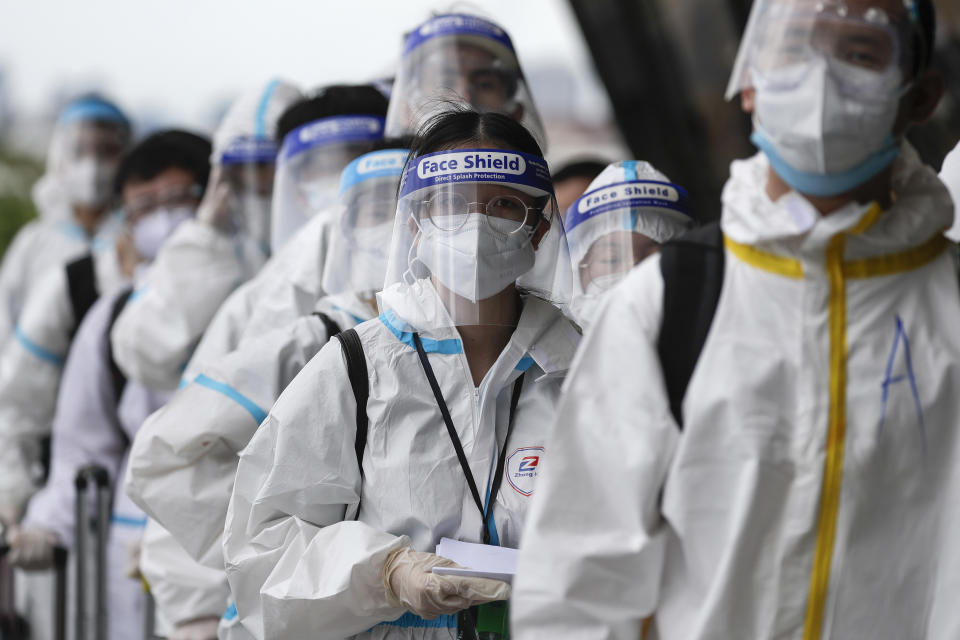 Foreign passengers wearing protective suits line up for their flight to China at Manila's International Airport, Philippines, Monday, Jan. 18, 2021. Coronavirus infections in the Philippines have surged past 500,000 in a new bleak milestone with the government facing criticisms for failing to immediately launch a vaccination program amid a global scramble for COVID-19 vaccines. (AP Photo/Aaron Favila)