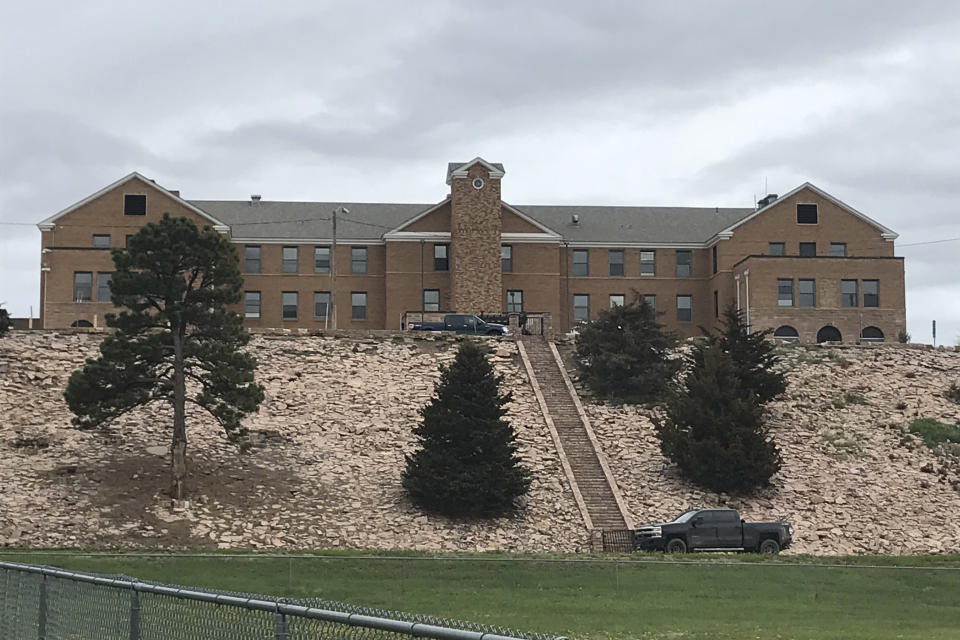 In this photo provided by Randi Oyan, is the former Rapid City Indian School, in Rapid City, S.D., on Wednesday, May 11, 2022. The school opened in the late 1800s and shut down in 1933. It was later converted into an asylum and a hospital, and now operates as an Indian Health Service clinic. A memorial is planned at a nearby hillside where researchers say dozens of boarding school children are buried in unmarked graves. (AP Photo/Randi Oyan)