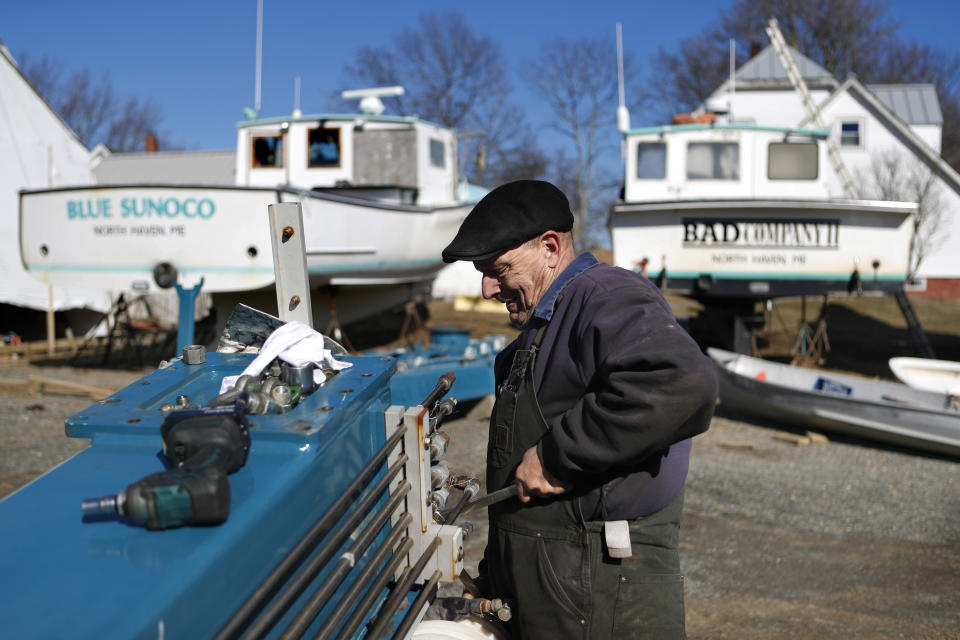 Todd Krause works on a boat lift in Brown's Boat Yard on March 16 on North Haven, Maine, where the Select Board voted to ban visitors and seasonal residents immediately to prevent the spread of the coronavirus to the island in Penobscot Bay. (AP Photo/Robert F. Bukaty)