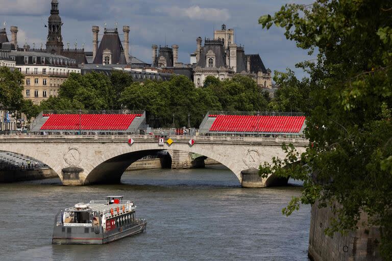 Un bateau navigue le long de la Seine en direction du Pont au Change, où des tribunes ont été installées en prévision des prochains Jeux Olympiques et Paralympiques de 2024 à Paris, le 10 juillet 2024.