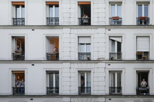 Des personnes à la fenêtre de leurs appartements applaudissent les personnels soignants, le 30 mars 2020 à Paris pendant confinement instauré en France - GEOFFROY VAN DER HASSELT, AFP/Archives