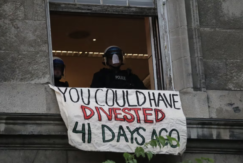 Montreal police wearing helmets eventually appeared inside the building after protesters blockaded themselves on what appeared to be the third floor. (Sarah Leavitt/CBC)