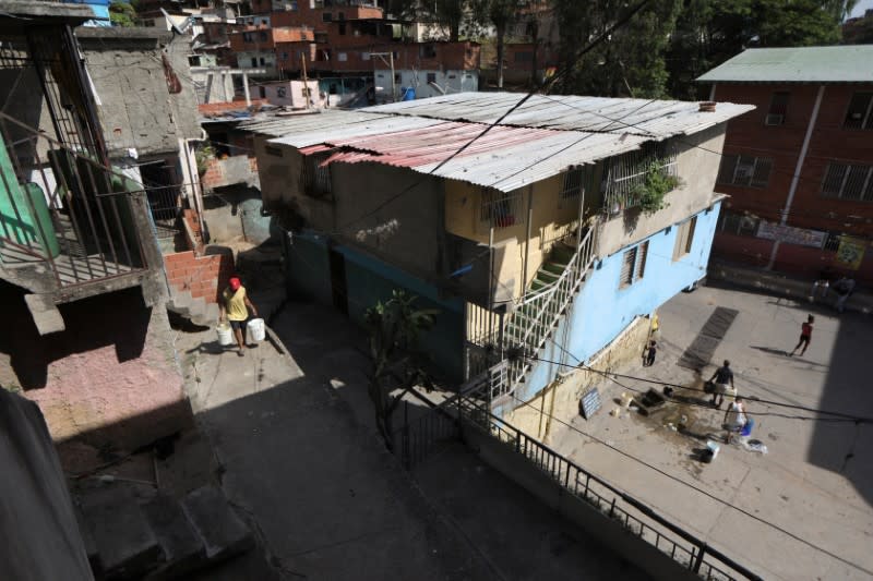 Jose Herrera walks carrying plastic buckets with water into his house in the low-income neighbourhood of Petare amid the coronavirus disease (COVID-19) outbreak in Caracas