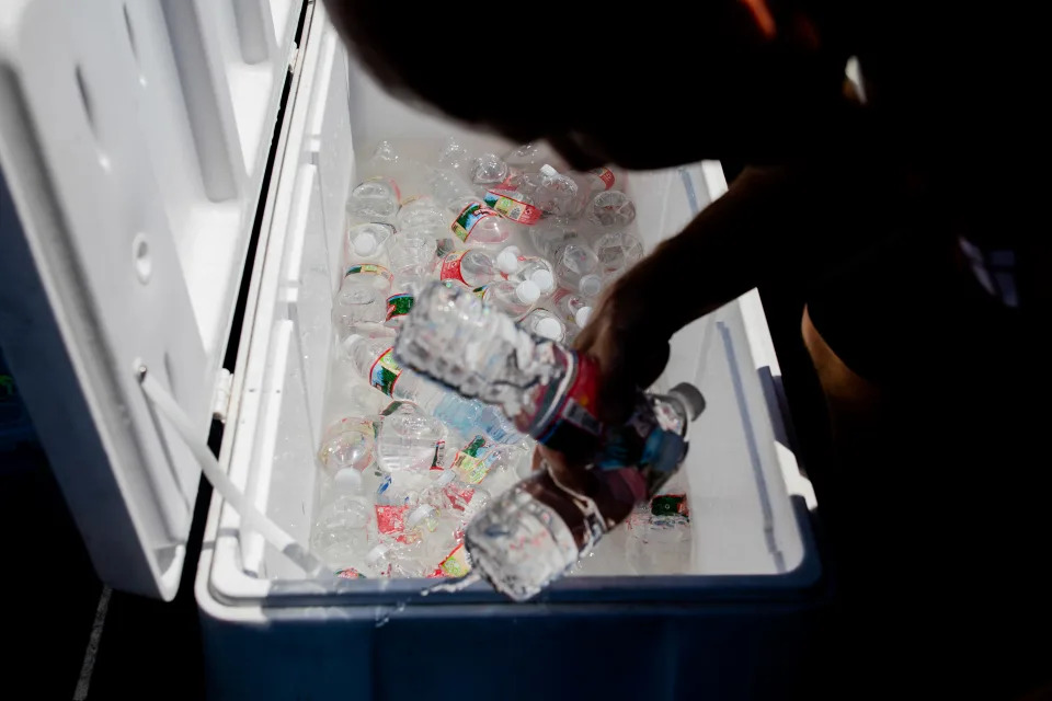 A worker with the Coachella Valley Rescue Mission's mobile outreach unit hands out bottled water in Indio, Calif., Sept. 6, 2022. (Alex Welsh/The New York Times)